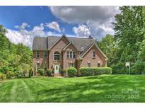 Beautiful brick home with a manicured lawn and mature trees, creating a welcoming exterior at 706 Evans Manor Dr, Weddington, NC 28104