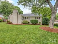 Charming single story home featuring a brick chimney, lush lawn, and mature trees for added curb appeal at 1227 Seneca Pl, Charlotte, NC 28210