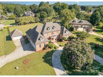 Expansive brick home showcasing meticulously manicured landscaping, mature trees, and a circular driveway at 150 Northchase Dr, Concord, NC 28027