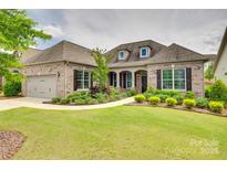 Beautiful brick home featuring a lush front yard with mature landscaping and an attached two-car garage at 15927 Vale Ridge Dr, Charlotte, NC 28278