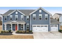Charming two-story home showcasing a blue exterior, red door, manicured landscaping, and an attached two-car garage at 1620 Callahan Rd, Fort Mill, SC 29715