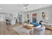 Bright open-plan living room with a modern kitchen, blue sofa, light wood floors and minimalist decor at 1829 Jennings St, Charlotte, NC 28216