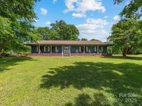 Charming blue home with a welcoming front porch and rocking chairs, set on a spacious lawn at 2500 Cedar Cove Dr, Harrisburg, NC 28075