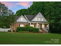 Charming brick home with a manicured lawn, covered porch, and lush green landscaping at 328 Whippoorwill Rd, Mooresville, NC 28117