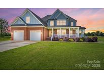 Charming two-story home boasts a welcoming front porch, two-car garage, and lush green lawn at 3707 Seagrave Farm Rd, Concord, NC 28025