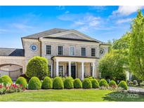 Elegant brick home featuring a columned front porch, manicured lawn and mature landscaping at 5917 Saint John Ln, Charlotte, NC 28210