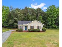 Charming single-story home with vinyl siding, blue front door, and manicured landscaping at 6022 Windsong Way, Wingate, NC 28174