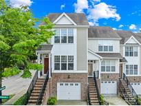 Charming two-story townhome with brick accents, garage, and inviting entryway staircase, framed by a lush green tree at 6429 Terrace View Ct, Charlotte, NC 28269