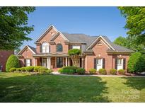 Stately brick home with manicured lawn, beautiful landscaping, and inviting front porch at 7507 Meadowgate Ln, Waxhaw, NC 28173