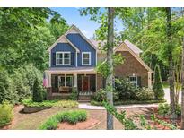 Charming two-story home featuring a mix of brick and blue siding, a welcoming porch, and lush landscaping at 1328 Huntcliff Dr, Waxhaw, NC 28173