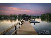 Lake house dock featuring bench seating and boat slip with picturesque views during sunset at 230 Shady Cove Rd, Troutman, NC 28166