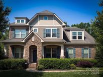 Charming two-story home with a brick and stone facade, complemented by lush greenery and professional landscaping at 4006 Tremont Dr, Indian Trail, NC 28079