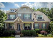 Charming two-story brick home featuring a stone entrance, covered porch, and beautifully landscaped front yard at 4006 Tremont Dr, Indian Trail, NC 28079