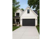 Charming two-story home with a black garage door, light grey driveway, and a well-manicured lawn at 418 Harrison St, Statesville, NC 28677