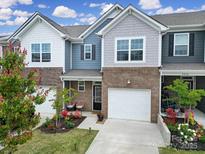 Charming townhome with brick accents, a one-car garage, and a beautifully landscaped front yard at 5034 Moss Pine Way, Tega Cay, SC 29708