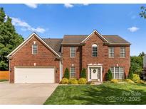 Charming two-story red brick home with a well-manicured lawn and beautiful landscaping at 611 Meadow Lake Dr, Matthews, NC 28105