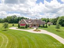 Beautiful home featuring manicured lawn, circular drive, mature trees, and attached garage at 8825 Harris Rd, Concord, NC 28027