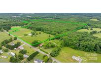 Expansive aerial view showcases a vast property with lush greenery and a mix of open fields and wooded areas at 9161 Paul Payne Store Rd, Stony Point, NC 28678
