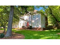 Charming two-story home with a red front door, lush lawn, and mature trees surrounding the property at 10338 Hollybrook Dr, Charlotte, NC 28277
