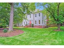 Charming two-story home featuring a well-manicured lawn and vibrant green trees on a sunny day at 10338 Hollybrook Dr, Charlotte, NC 28277