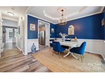 Bright dining room featuring blue accent wall, white wainscoting, and a modern chandelier at 108 N Arcadian Way, Mooresville, NC 28117