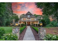 Beautiful home exterior featuring a manicured lawn, inviting front porch, and professionally landscaped walkway at 157 Dedham Loop, Mooresville, NC 28117