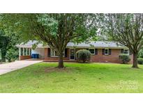Charming brick home featuring a covered carport, mature trees and lush landscaping at 1753 28Th Ne St, Hickory, NC 28601