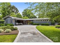 Charming gray single-story home featuring a concrete driveway, landscaped front yard, and a unique carport at 2121 Valencia Ter, Charlotte, NC 28226