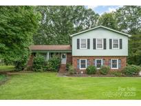 Charming two-story home featuring a brick facade, light green siding, and a well-manicured lawn at 5772 Gettysburg Nw Dr, Concord, NC 28027