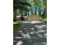 Charming single-story home featuring a large driveway and attached two-car garage in a tranquil, wooded setting at 64 Timberidge Dr, Lake Wylie, SC 29710