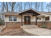 Charming home entrance featuring a stone facade, covered porch, and a beautiful dark wood front door with decorative glass at 64 Timberidge Dr, Lake Wylie, SC 29710
