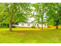 Charming single-story home featuring a lush front yard and a covered parking area, surrounded by mature trees at 745 Rock Castle Dr, York, SC 29745