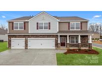 Beautiful two-story home with a three car garage, brick accents, lush lawn, and a covered porch at 8025 Kennesaw Dr, Gastonia, NC 28056
