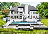 Stunning backyard with a modern pool, integrated spa, outdoor kitchen, and ample patio space for entertaining at 1001 Berwick Ct, Waxhaw, NC 28173