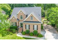 Charming brick home with well-maintained landscaping, mature trees, and a paved driveway leading to the garage at 11724 Brambleton Ct, Charlotte, NC 28277