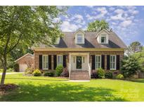 Charming brick home featuring a landscaped front yard and dormer windows at 1208 Chausley Ct, Charlotte, NC 28211