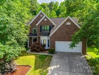 Charming brick home featuring a well-manicured lawn and a two-car garage, nestled among lush green trees at 12719 Vantage Point Ln, Huntersville, NC 28078
