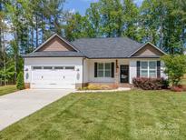 Charming single-story home featuring a two-car garage, manicured lawn, and delightful landscaping at 142 Highland Dr, New London, NC 28127