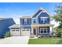 Charming two-story blue home features a manicured lawn, a two car garage, and covered porch at 2327 Glenway Trail Ct, Pineville, NC 28134