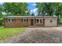 Charming brick home featuring a chimney, dark shutters, and inviting front entrance at 2401 Woodleaf Dr, Gastonia, NC 28052
