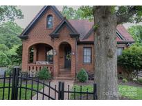 Charming brick home featuring an arched porch, black trim, and a well-maintained front yard with mature tree at 324 N 5Th St, Albemarle, NC 28001