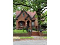Charming brick home with a unique roof, arched entryway, black iron fence, and lush landscaping at 324 N 5Th St, Albemarle, NC 28001