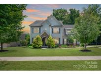 Charming two-story home with a manicured lawn, mature trees, and stone accents around the entrance at 4225 Abernathy Pl, Harrisburg, NC 28075