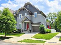 Charming two-story home features a gray exterior, red front door, attached garage and well-manicured lawn at 5210 Kelly St, Charlotte, NC 28205