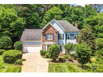 Charming two-story home with a lush lawn, mature trees, brick and blue siding, and an attached two-car garage at 5238 Downing Creek Dr, Charlotte, NC 28269