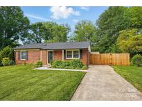 Charming brick home featuring a well-manicured lawn, mature trees, and a private driveway at 529 Dedmon Dr, Charlotte, NC 28216