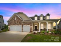 Charming single-Gathering home showcasing a stone facade, two-car garage, and inviting front porch area at dusk at 7010 Brush Crk, Monroe, NC 28110