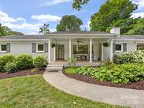 Charming brick home featuring a covered porch with rocking chairs and landscaped front yard at 1031 Eldorado Ave, Charlotte, NC 28262