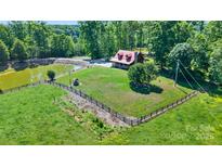 Stunning aerial view of a charming home with a pond, surrounded by lush greenery and a fenced yard at 11227 Cool Springs Rd, Cleveland, NC 27013