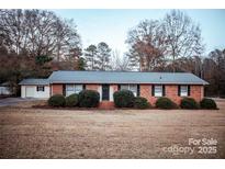 Charming brick ranch home with manicured bushes, dark shutters and a spacious front yard at 1708 Dogwood Ln, Lancaster, SC 29720
